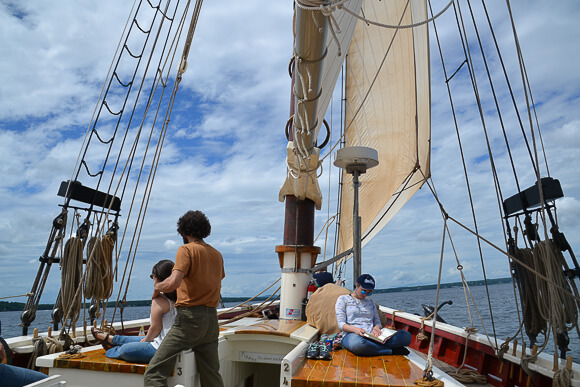 Man and two women relaxing on a windjammer with sail up