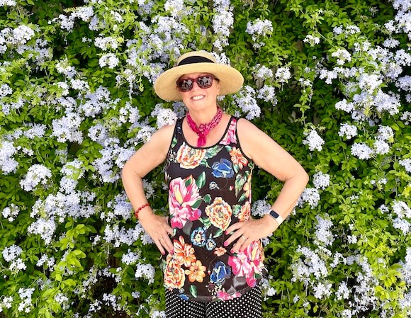 woman in colorful top in front of flowers