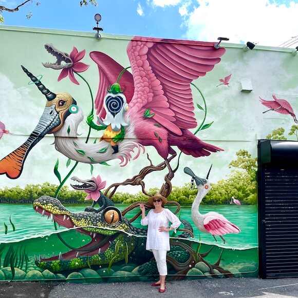Woman in white standing in front of colorful street art mural of the Everglades