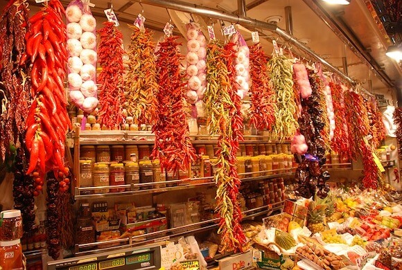 peppers and garlic hanging at a fresh market stall