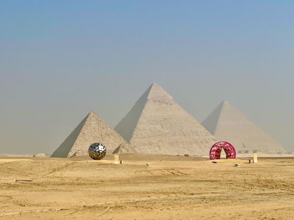 Three pyramids of Giza with sculptures in front.