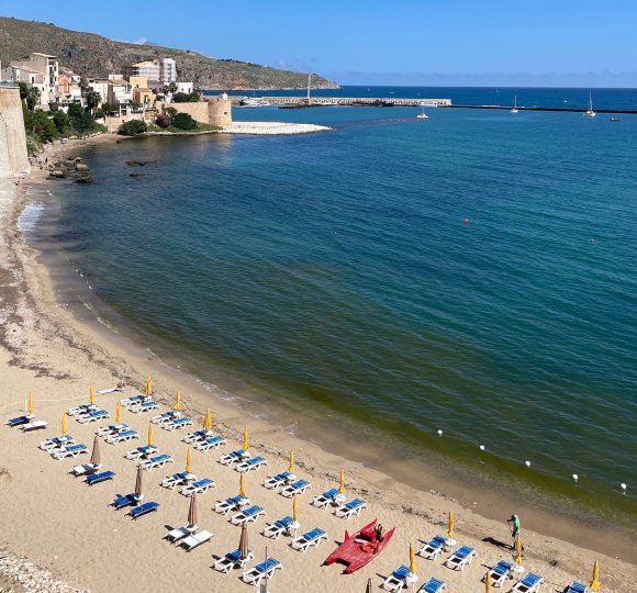 Beach lined with chaise lounges overlooking the sea of Castellammare. 