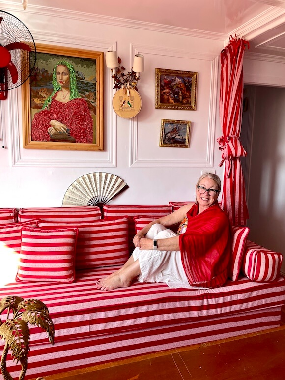 Woman in red and white sitting on couch with pink and red stripes on dahabiya cruise.