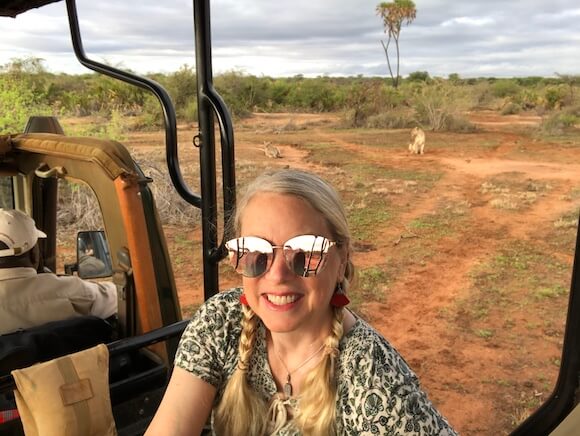 woman with sunglasses and lion in background