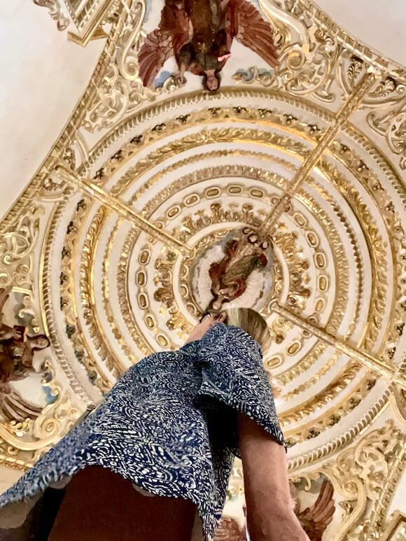woman looking up at baroque ceiling in church