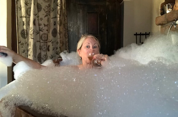 woman in bubble bath drinking wine