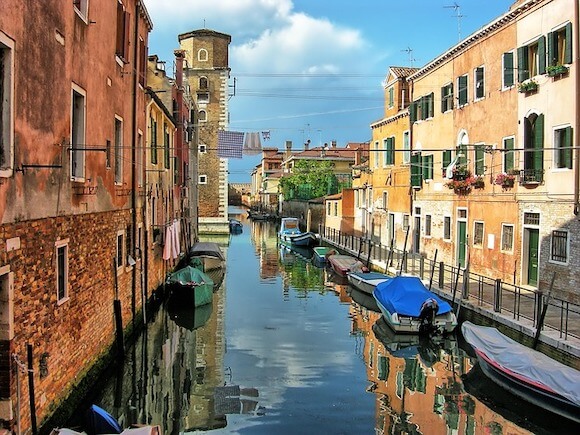 A quiet canal in Venice with no crowds, lined with historic buildings and boats, ideal for travelers seeking peace and authenticity.